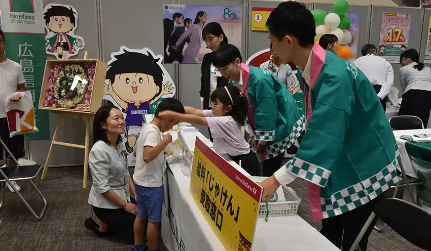 広島信金ブースで給与を受け取るイベント参加者（左から2人目、8月24日、イオンモール広島府中）