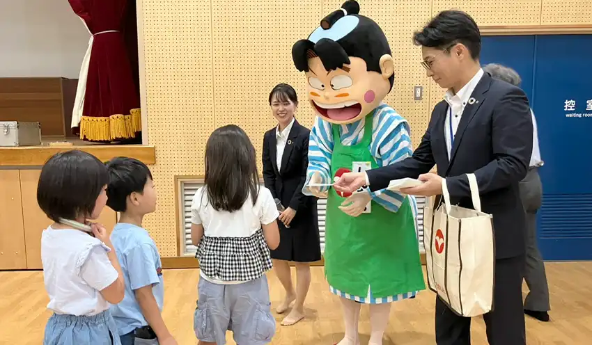 尼崎信金のキャラクター・しんちゃんからおこづかい帳をもらう児童たち（8月18日、西宮市立高木小学校）