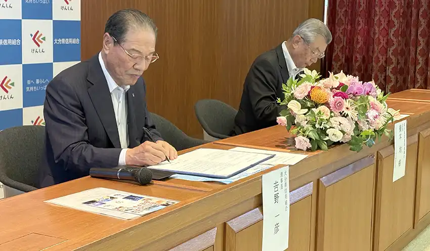 協定書に署名する𠮷野理事長（左、9月2日、本店）