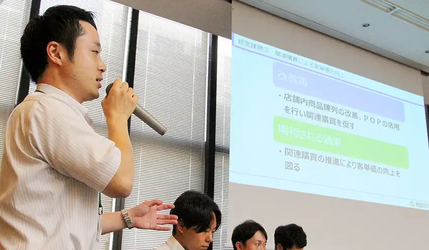 担当した小売業者の現状分析や経営改善策を発表するメンバー(9月24日、本店)