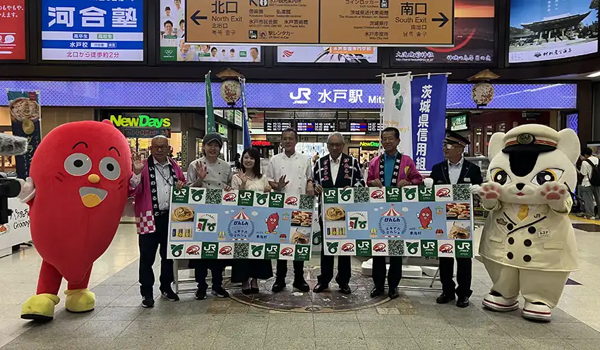 東海村マスコットキャラクター・イモゾー（左）とJR東日本水戸支社キャラクター・ムコナちゃん（右）に囲まれ、マルシェ開催を宣言する関係者（9月3日、水戸駅改札前催事スペース）