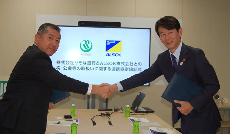 連係協定を締結して握手する髙橋・ALSOK常務執行役員（左）、大森・りそな銀執行役員（9月24日、りそなホールディングス本社）