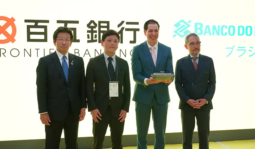 百五銀の川上取締役常務執行役員（左）と萬古焼を手にするブラジル銀東京支店長（左から3人目、8月26日、大阪市）