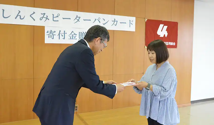 山下代表に目録を手渡す田中監事(左、9月12日、佐賀東信組本店)