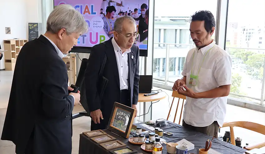 出展者（右）に質問する京都北都信金の森田悦夫地域創生事業部長（左）と吉岡美和理事（9月19日、QUESTION）