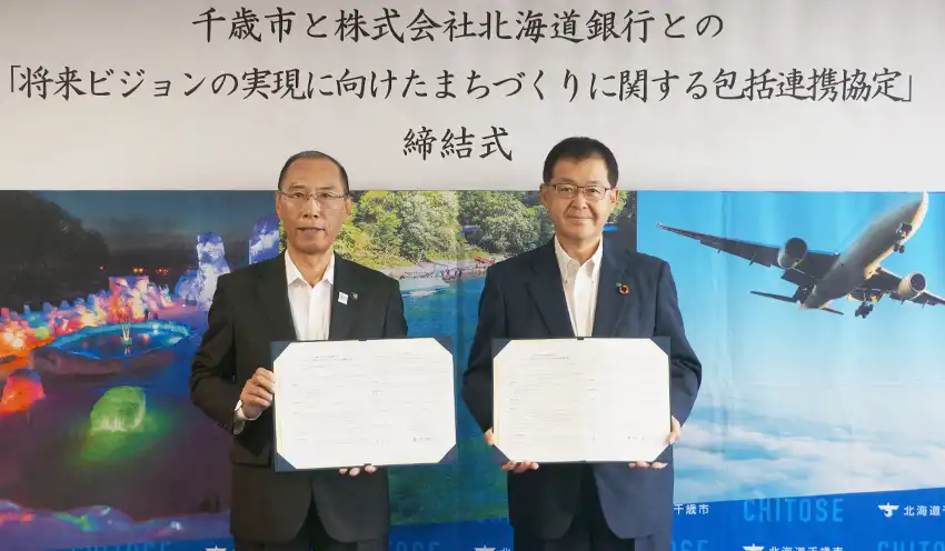 協定書を持つ横田市長（左）と兼間頭取（9月18日、千歳市役所、北海道銀提供）