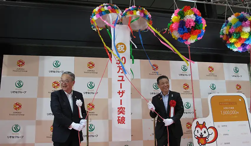 くす玉を開けた（左から）十六FGの池田社長とりそなHDの南社長（9月10日、十六FG本社前）