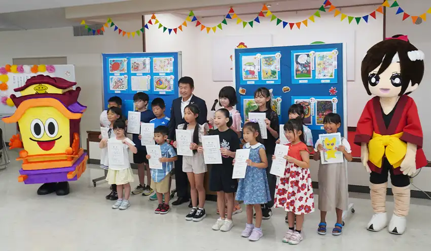 古田理事長やイメージキャラクターの「だし太郎」（左端）「まつりちゃん」（右端）と記念撮影する入賞者（9月13日、半田信金本店）
