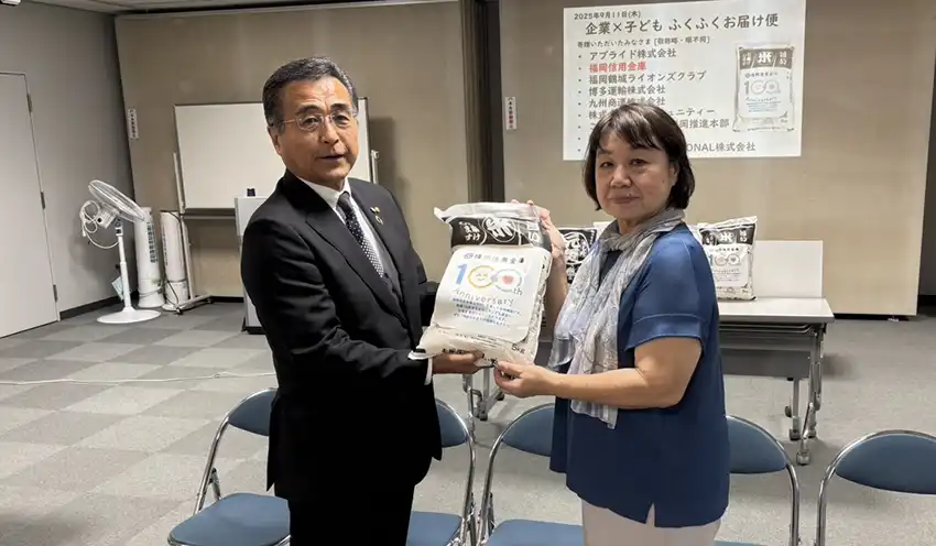食料品を手渡す野見山理事長（左、9月11日、福岡市市民福祉プラザ、福岡信金提供）
