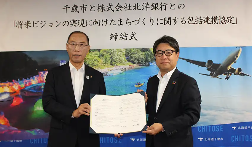 協定書を掲げる横田隆一・千歳市長（左）と津山頭取（9月9日、千歳市役所）
