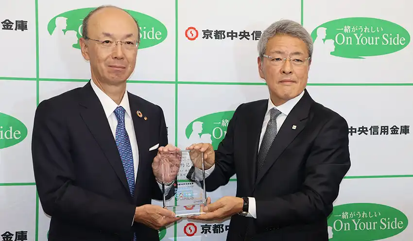 発表後、撮影に応じる（左から）植村理事長、日本ウエスト・長田和志社長（9月8日、京都中央信金本店）