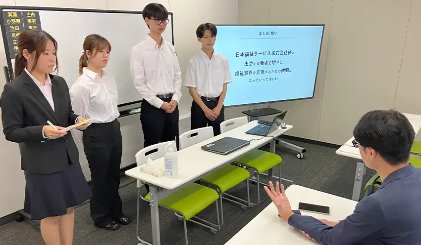 プレゼンした学生に感謝をのべる江尻氏（手前、9月2日、日本福祉サービス）