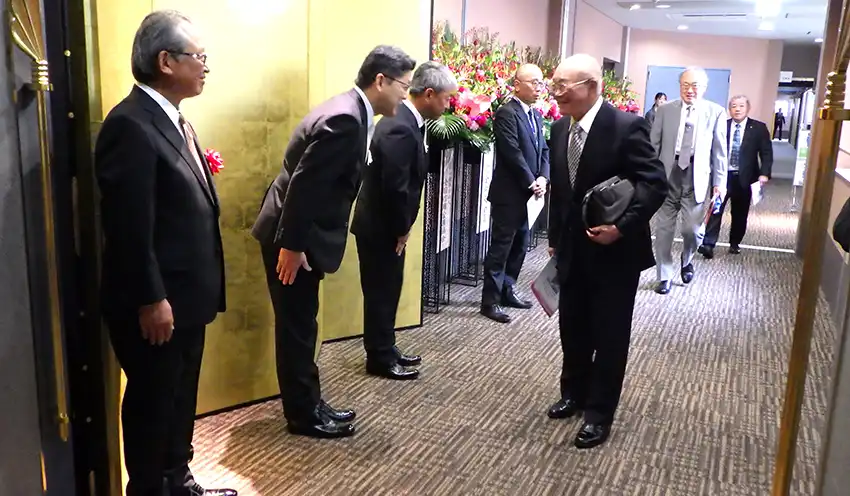 来場者を立礼で迎える（左から）小池貞志・前理事長、宮嶋理事長、木下博文専務理事（9月20日、飯田市・シルクプラザ）