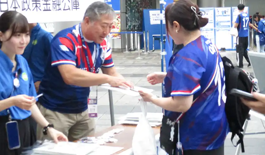 来場者に缶バッジを渡す横浜信金職員（9月20日、横浜信金提供）
