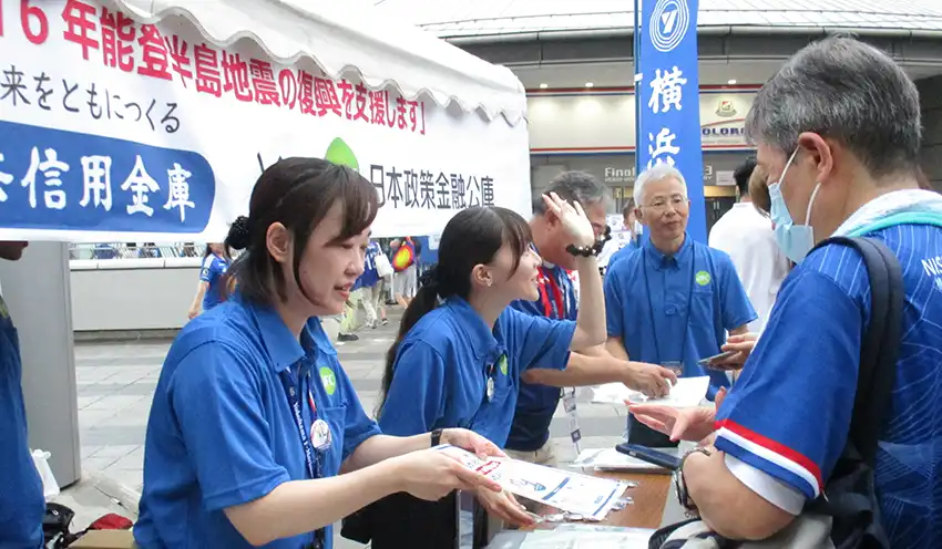 来場者にパンフレットを渡す日本公庫職員（9月20日、横浜信金提供）