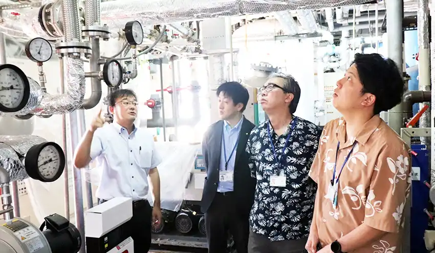 省エネ化したボイラーなどを説明する(左から)今村社長、鹿屋係長、指宿支店の山元暢寿支店長、鳩宿敬祐融資代理(10月2日、指宿市の「こころの宿」)