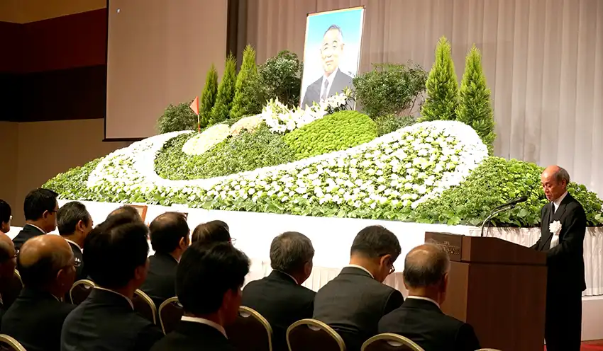 実行委員長としてあいさつする飯田理事長（右、10月27日、ロイヤルパインズホテル浦和）