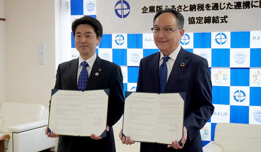 協定書を手にする小山市長(左)と清水常務(10月30日、みよし市役所)