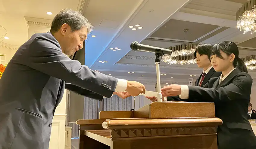 内定通知書を手渡す山口FGの岡田健吾執行役員経営統括本部長兼IT・業務統括本部長（10月1日、下関市内）