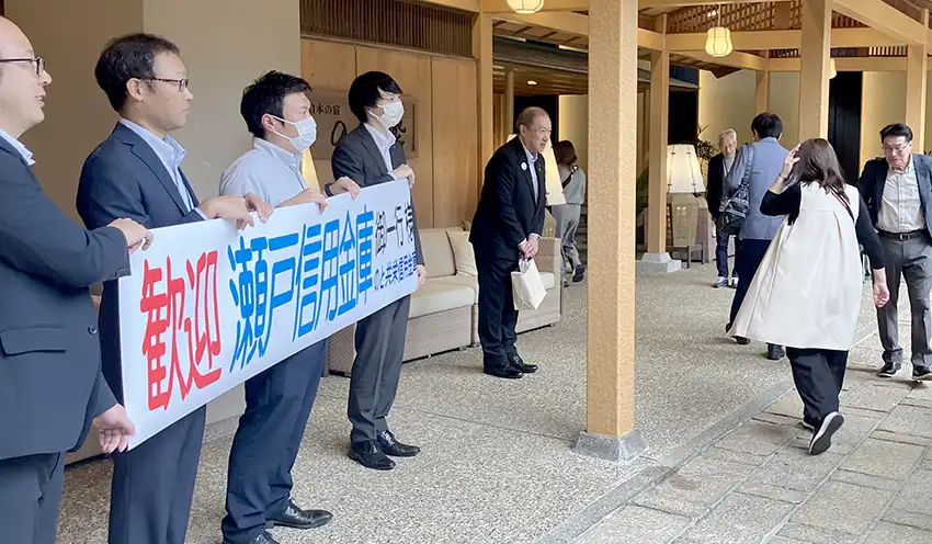 旅行者を出迎える鈴木会長（左から5人目）（10月14日、七尾市内）