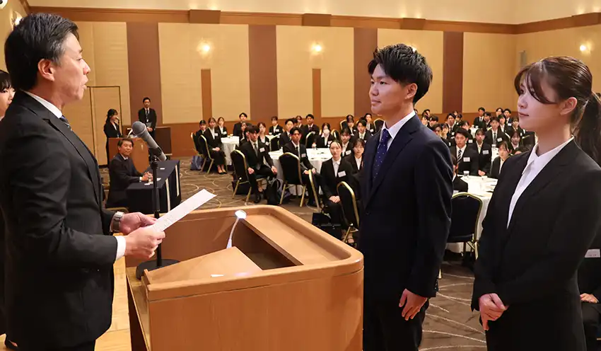 福岡銀の簡貴弘人事部長（左）から代表で内定通知書を受け取った鮫島海翔さんと庄野崎さん（右、10月1日、西鉄グランドホテル）