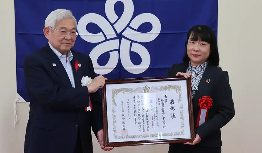 生嶋亮介副知事（左）から小湊取締役常務執行役員（右）に表彰状が手渡された（10月22日、福岡県庁）
