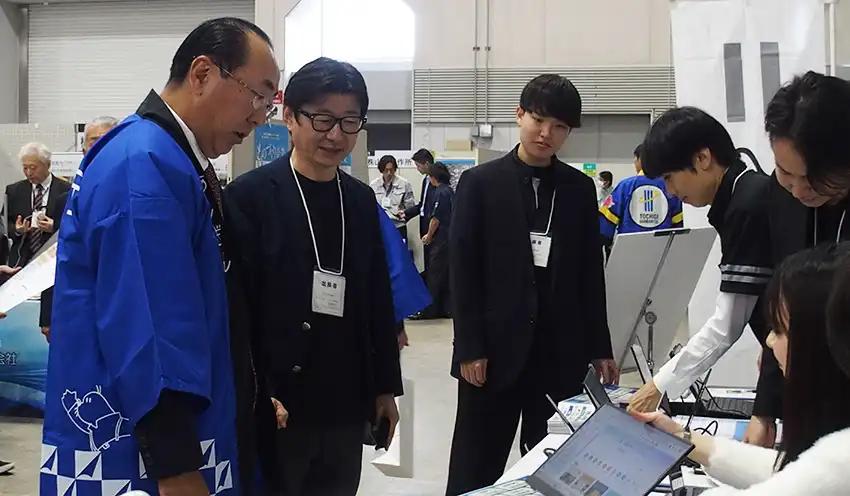 ソフトバンクのブースでAIソリューションの説明を受ける清水頭取(左、10月21日、マロニエプラザ)