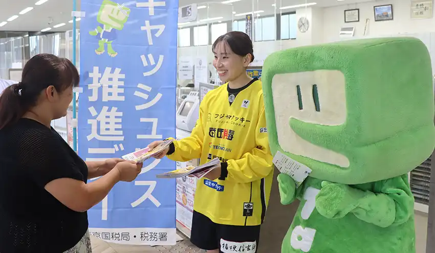 来店客（左）に電子納税を促す片山選手（中）とイータ君（10月10日、甲斐支店、甲府信金提供）