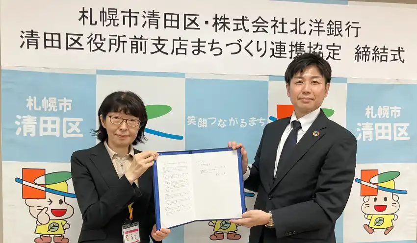 協定書を持つ札幌市清田区の浅山区長（左）と北洋銀行清田区役所前支店の赤星支店長（10月2日、札幌市清田区役所）