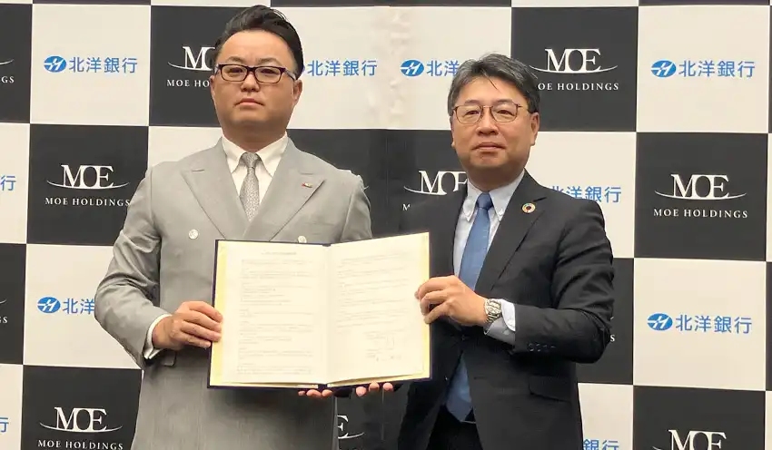 協定書を掲げるＭＯＥホールディングスの水戸社長（左）と津山頭取（10月22日、北洋大通センター）