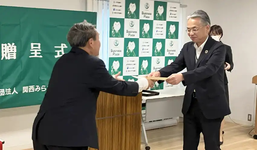 学校の代表者に贈呈書を授与する西山理事長（右、10月23日、ビジネスプラザおおさか）
