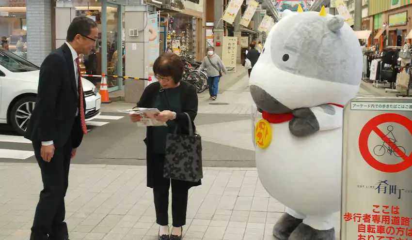 通行人に頒布物を配る「とうしくん」（右）と千田所長（左、10月15日、盛岡市内）