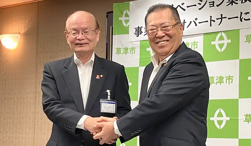 協定締結後、笑顔で握手する橋川市長（左）と久保田頭取、10月29日、草津市役所）