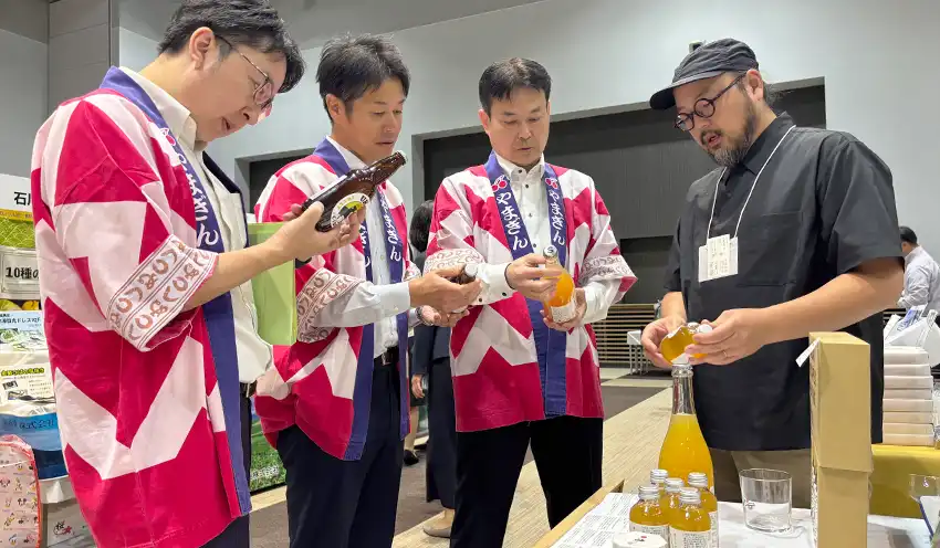 リンゴを使った「リンゴリらっぱ」を紹介する「日々」の佐藤春樹社長（右）から話を聞く山形銀の（左から）コンサルティング部の鈴木俊介副部長、樋口俊一部長、五百川常務執行役員（10月15日、仙台国際センター）