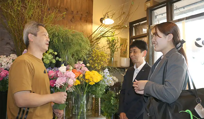 生花店の店長（左）と話す中田支店長（同2人目）と渉外係の浅松遥さん（10月2日、フラワーショップアスター）