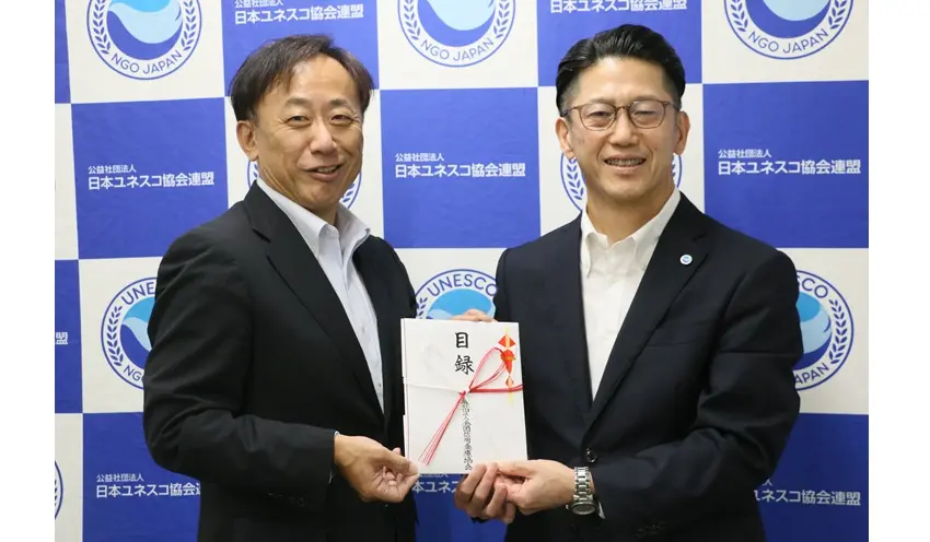 菅野常務理事（左）から日本ユネスコ協会連盟の東優介事務局長に目録が手渡された（10月9日、東京都渋谷区）