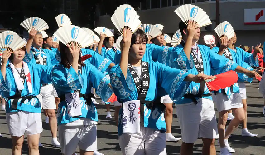 紅白の扇子を使い独自の踊りで会場を盛り上げる南日本銀の行員（11月3日、鹿児島市）